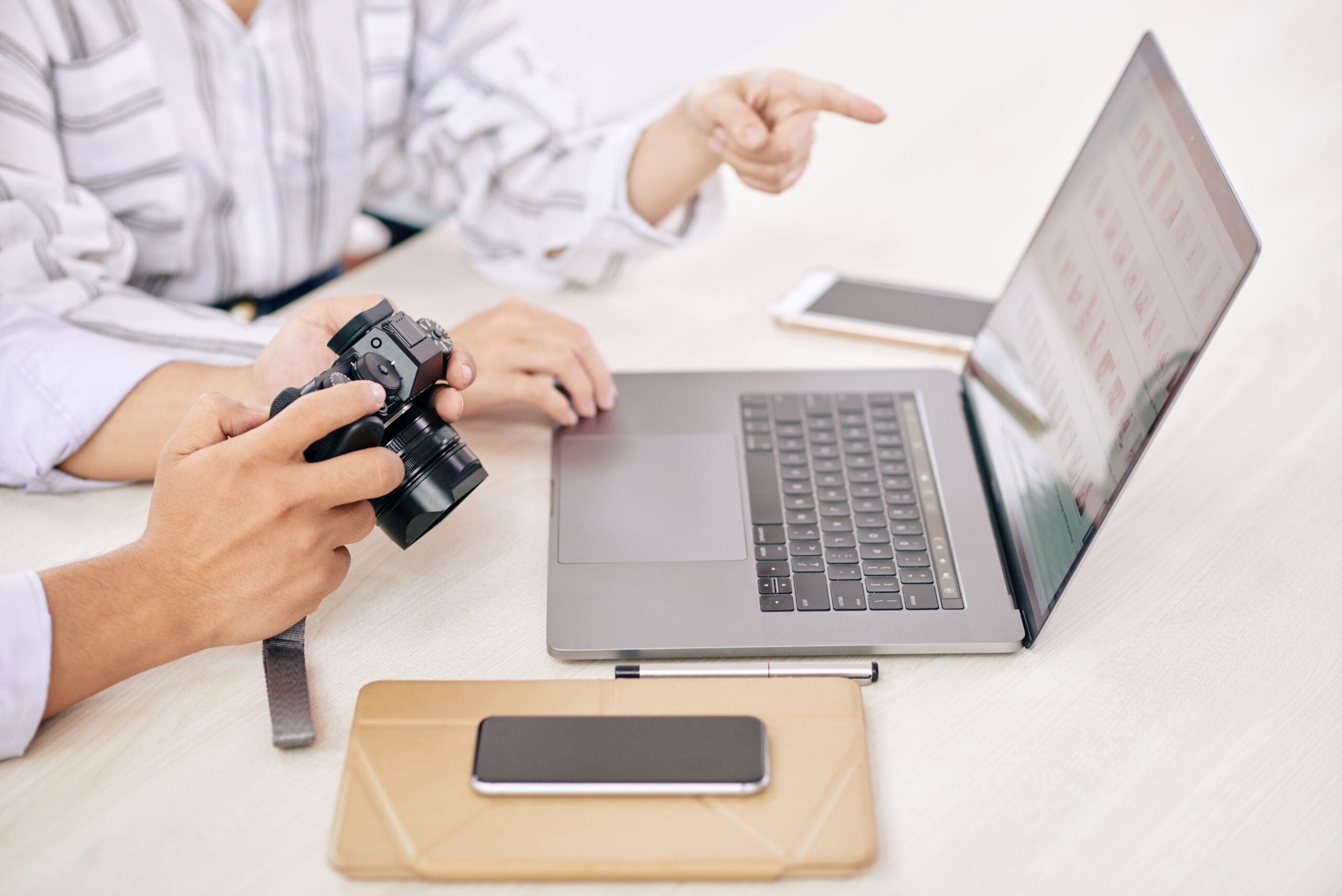 Coworking photographers with gadget at desk